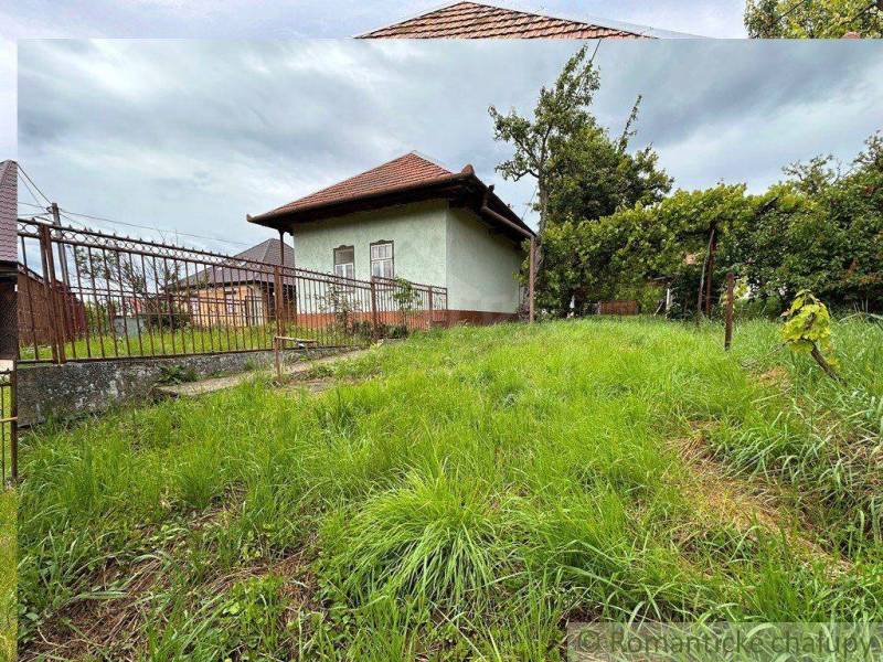 A cottage with a spacious garden in Nové Zámky, surrounded by a fence and trees.