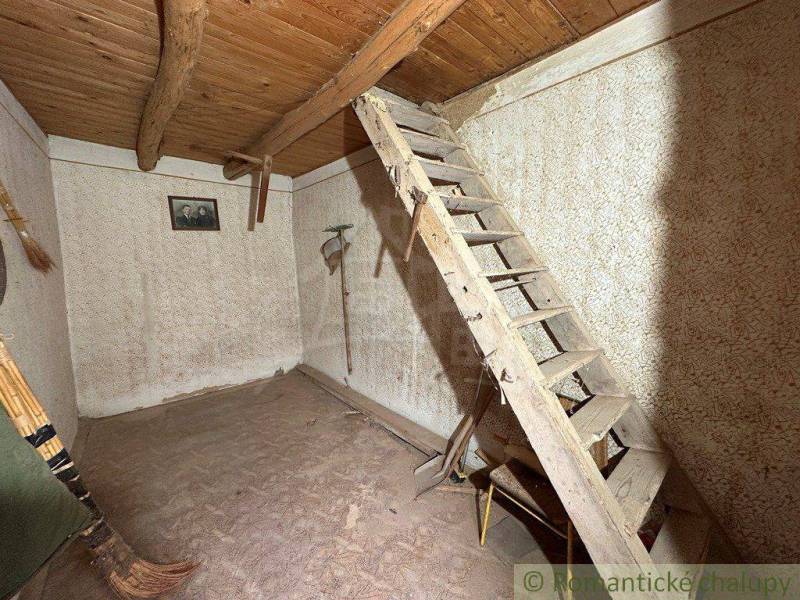 Wooden stairs lead to the attic in a simple room in the cottage.