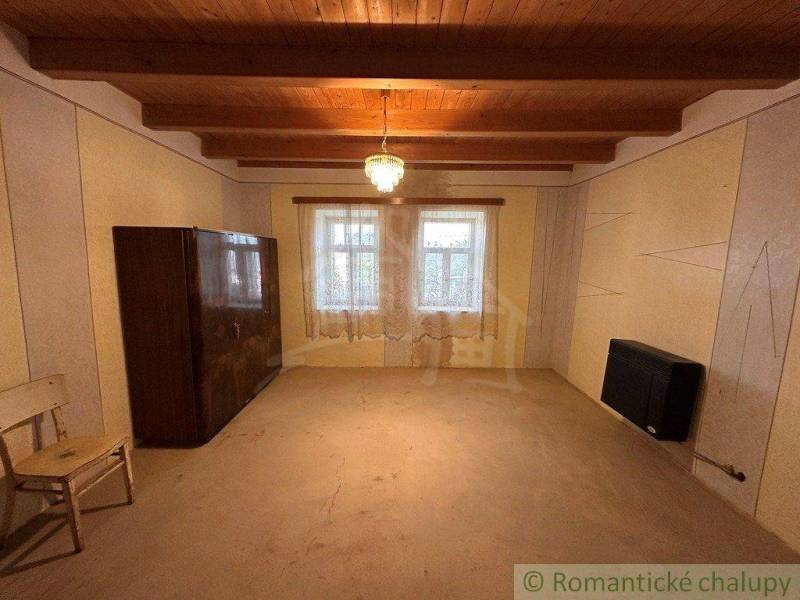 Wooden ceiling in a cabin room with simple furnishings and a central lamp.