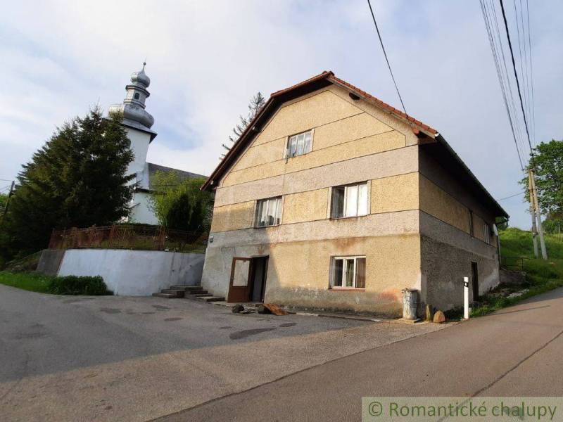 A family house near the church in Žiar nad Hronom with a large tree and power lines.