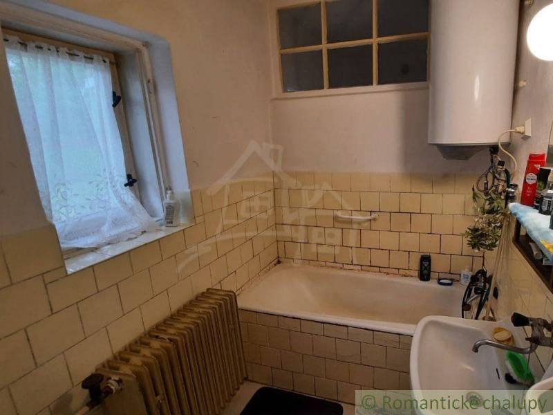 A bathroom in a family house with older tiles and an enamel bathtub.
