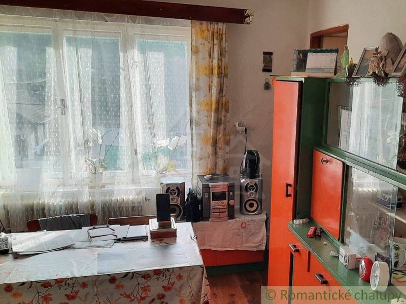 A room in a family house with a table, wardrobes, and a window with curtains.