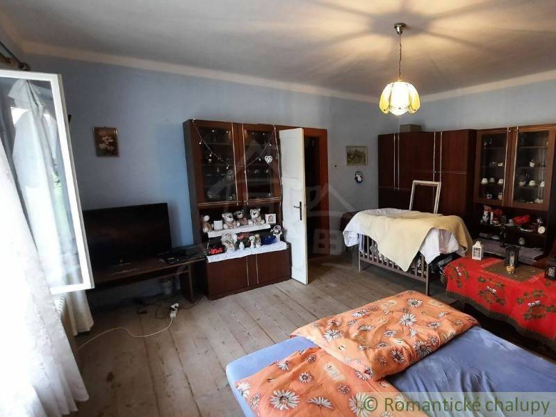 Bedroom in a family house with a bed, wooden floor, and wardrobes.