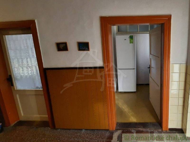 Interior of a family house with a door leading to the kitchen, visible white refrigerator.
