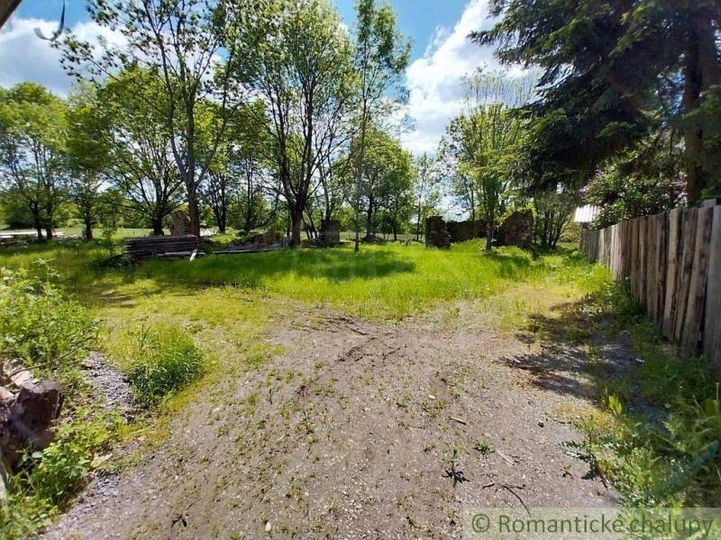 A grassy yard surrounded by trees and a wooden fence in Ábelová near the cottage.