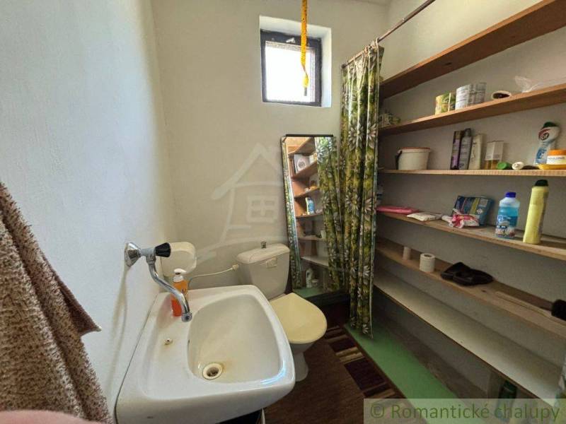 Bathroom in a family house with a sink and shelves full of cleaning supplies.