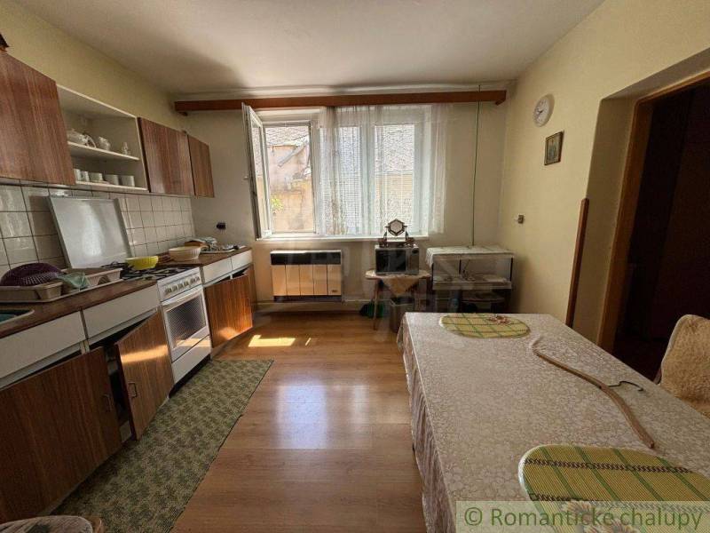 A kitchen in a family house with wooden furniture, a stove, and a dining table.