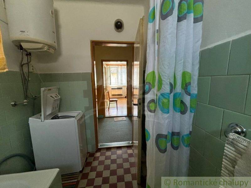 A bathroom in a family house with a washing machine, shower curtain, and gas boiler.