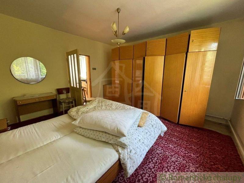 Bedroom in a family house with a bed, a large wardrobe, and a mirror on the wall.