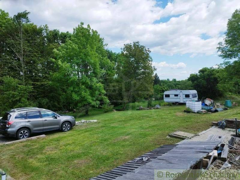 The surroundings of the cottage in Veľký Krtíš with a parked car and caravan on the lawn.
