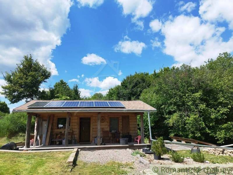 Wooden cabin near Veľký Krtíš with solar panels in a natural environment.