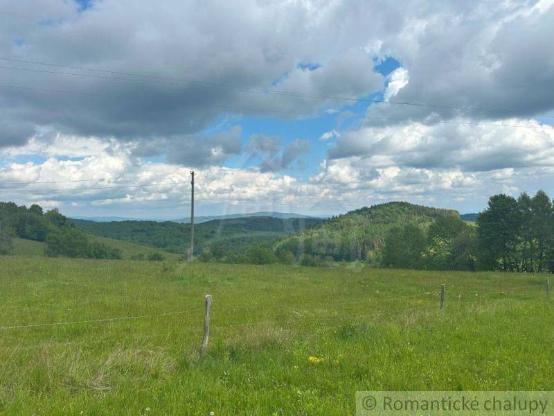 The landscape in České Brezovy with green gardens, hills, and a cloudy sky.
