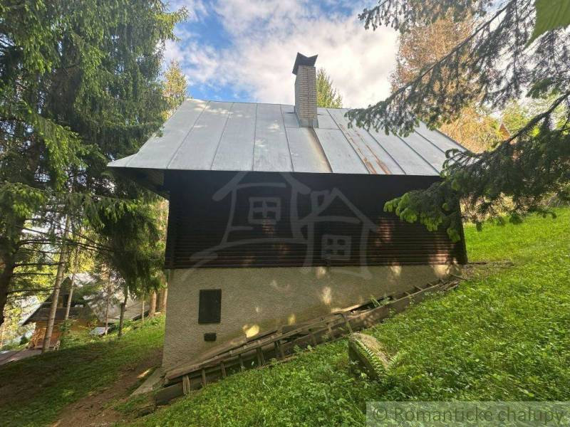 A cabin in the middle of the forest in Kokava nad Rimavicou with an iron roof and wooden walls.
