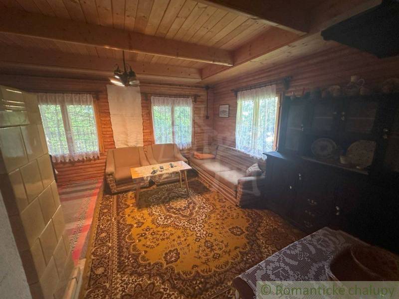 Traditional cottage interior with wooden walls, comfortable seating, and decorations.