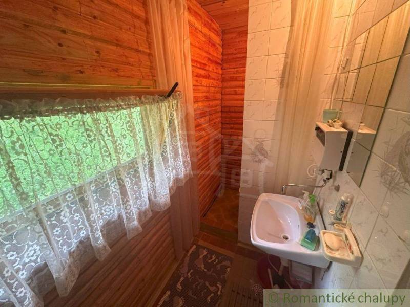 A cozy bathroom in a wooden cabin with a sink and a shower, decorated with curtains.