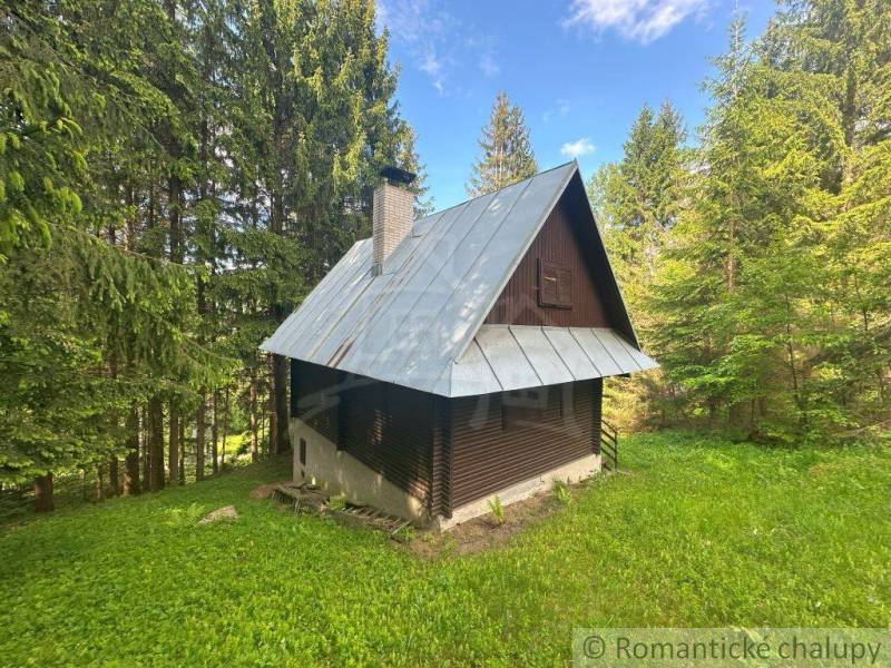 A cottage in the forest near Kokava nad Rimavicou, surrounded by greenery and trees.