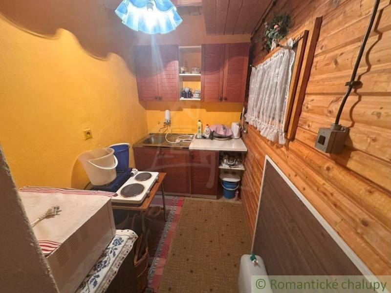 A kitchen in a cottage with wooden paneling, yellow walls, and kitchen equipment.