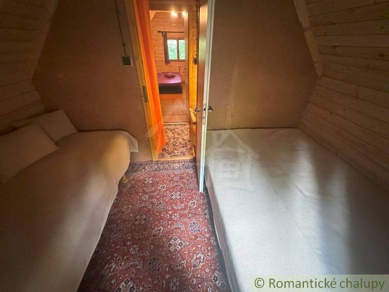 Interior of a cabin with two beds, a carpet, and a door to another room.
