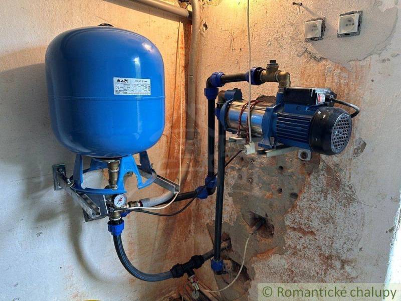 A device with a blue pressure tank in the technical room of the cottage.