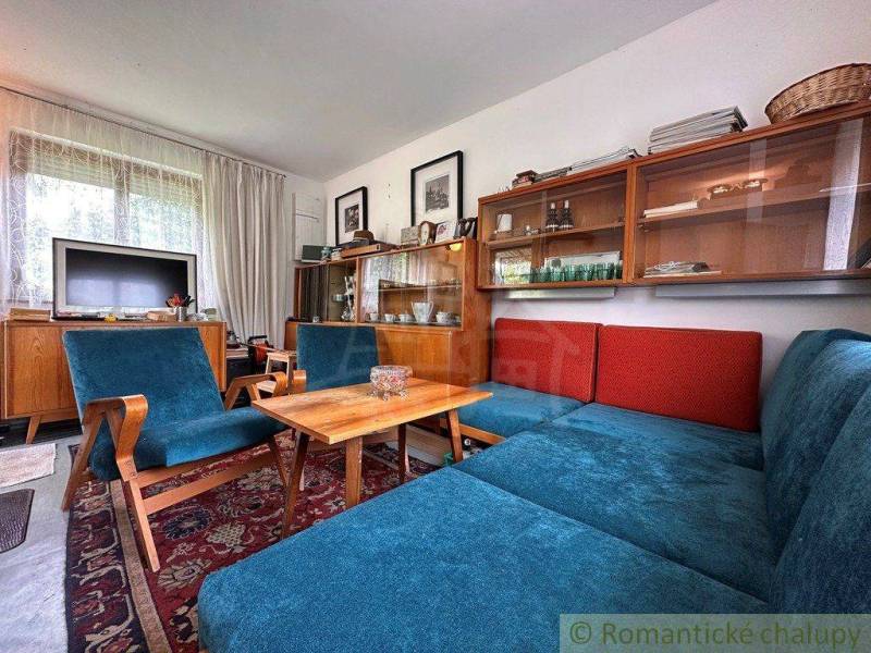 Living area of the cottage with a blue sofa, vintage furniture, and a television.