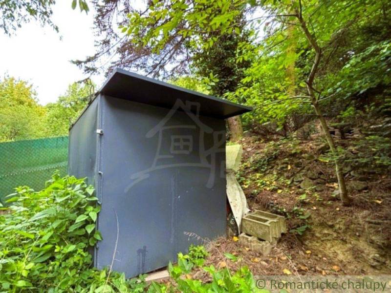 A metal shed surrounded by greenery in the forest near a cottage in Lamač, Bratislava.