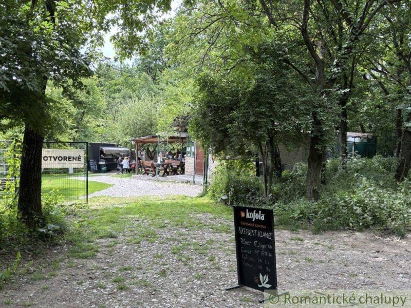 A forest cabin in Bratislava - Lamač with a seating area, surrounded by trees and greenery.