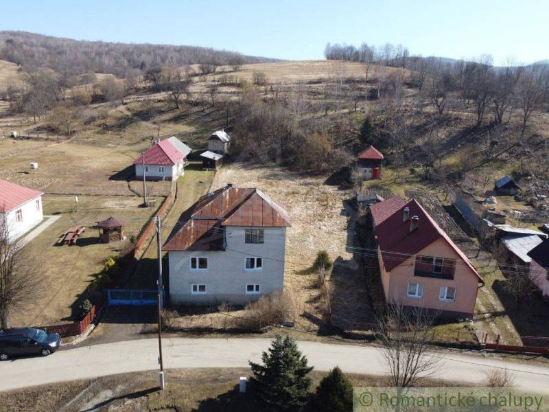 Family houses in Nová Sedlica surrounded by hills and fields with visible buildings and a road.