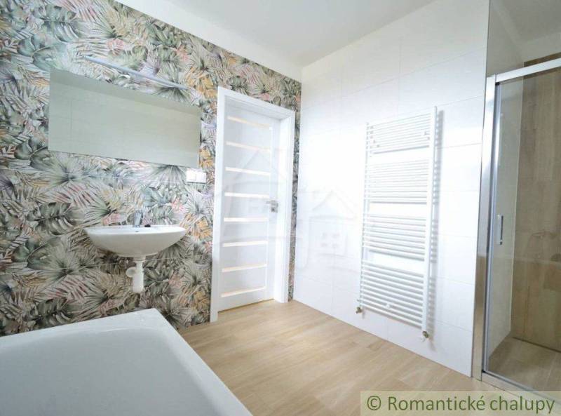 A bathroom in a family house with floral wallpaper, a sink, and a shower enclosure.