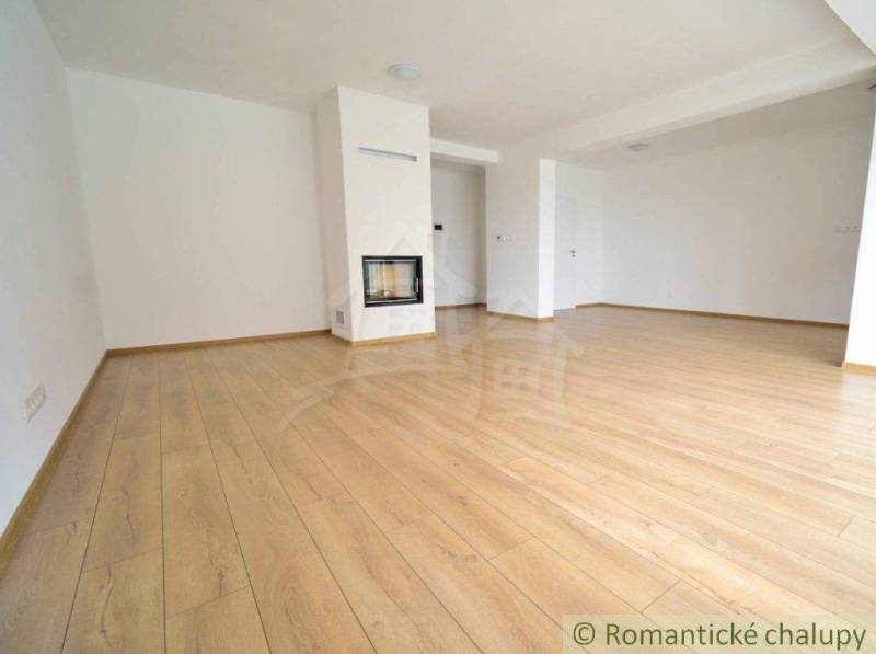 A spacious room with a wooden floor and a fireplace in a family house.