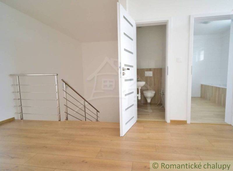 Wooden floor, two white doors, staircase, and bathroom in a family house.