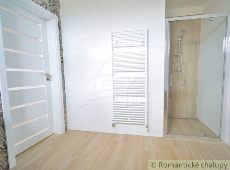 A bathroom in a family house with sliding doors, a shower corner, and a radiator.