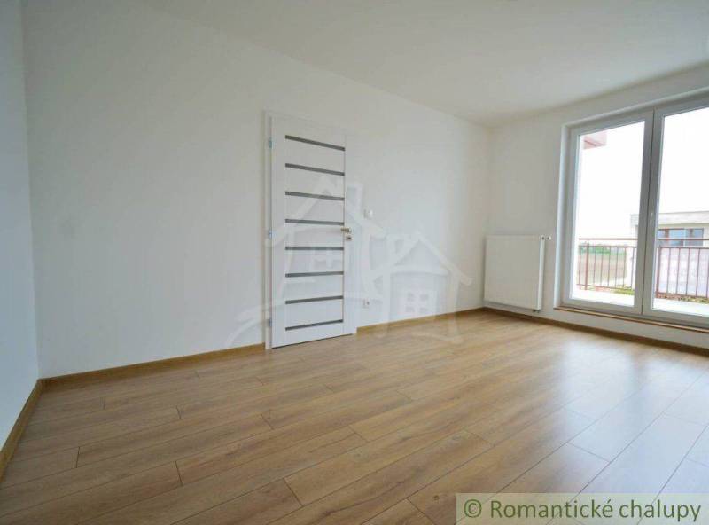 An empty room with a wooden floor and balcony doors in a family house.