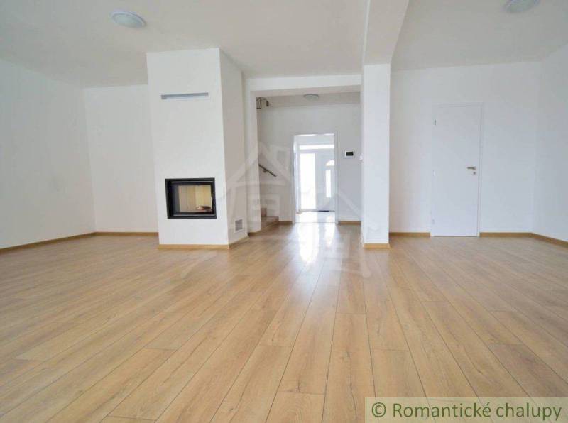Spacious living room with a fireplace and wooden floor in a family house.