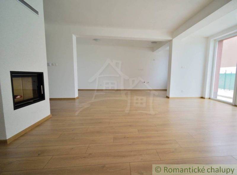 A spacious room with a fireplace and wooden floor in a family house.