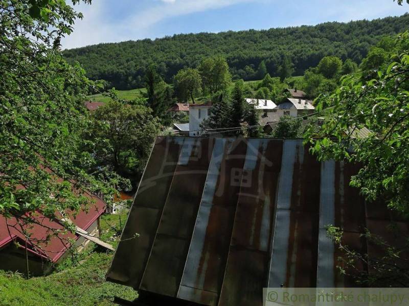 A family house in Hačava surrounded by greenery and other houses in a mountainous landscape.