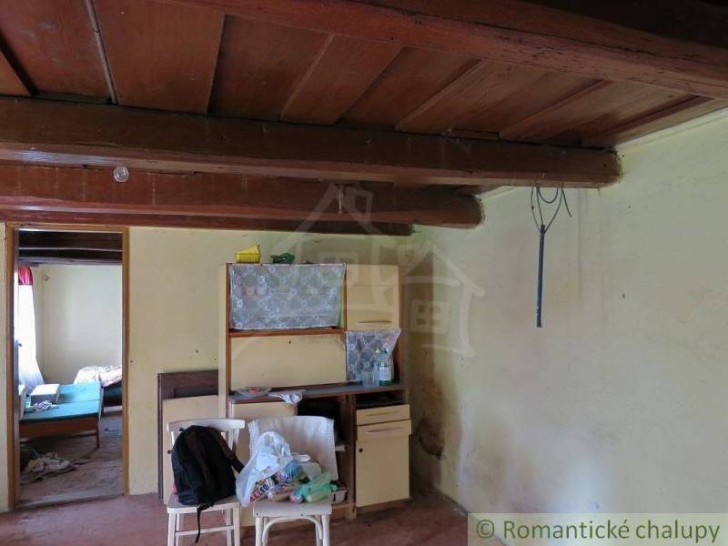 A room in a family house with a wooden ceiling, old furniture, and clutter.