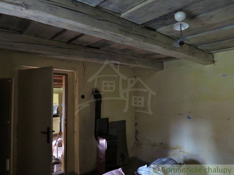 An old interior with a wooden ceiling and a tiled stove in a family house.