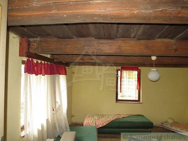 Interior of a family house with a wooden ceiling, bed, and curtains.