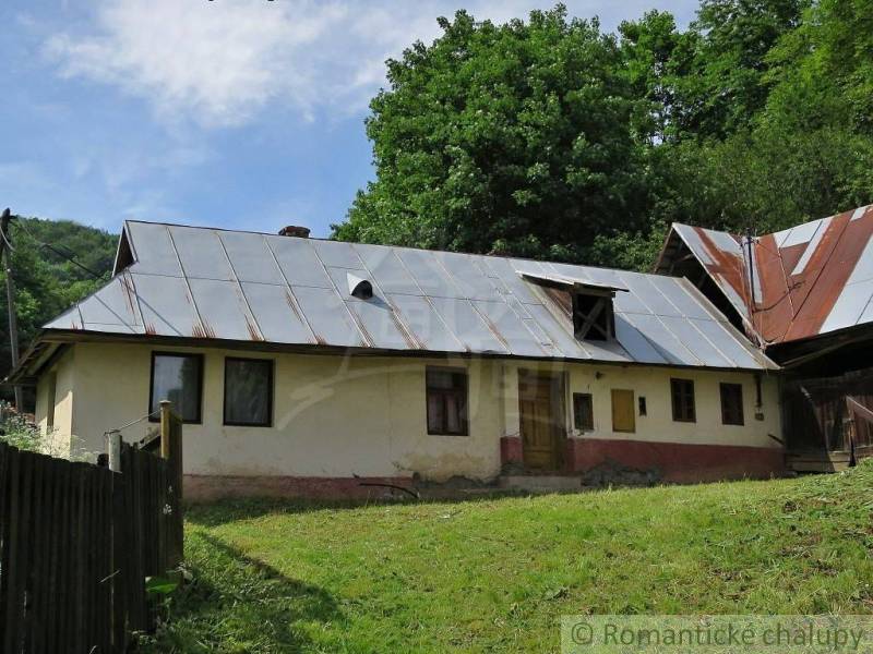 A family house in Hačava with a metal roof, surrounded by lush greenery.