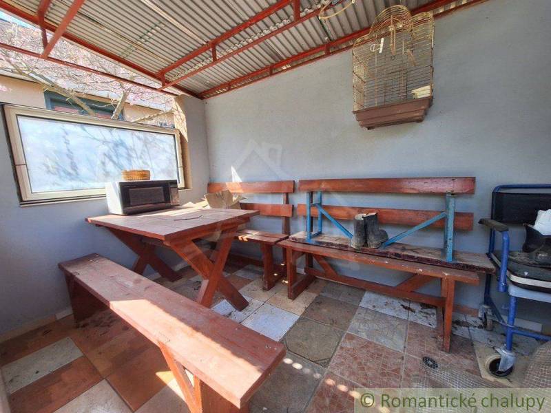 Wooden interior with a bench, table, window, and birdcage in a cabin.