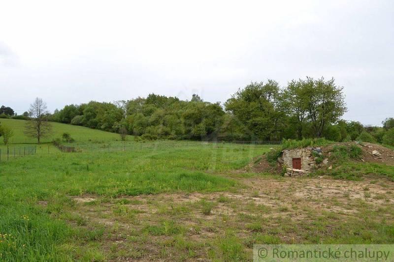 Gardens in Kečkovce with a lawn and a small stone entrance surrounded by trees.