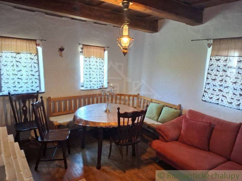 Rustic interior of a cottage with wooden furniture, a bench, and chandeliers.