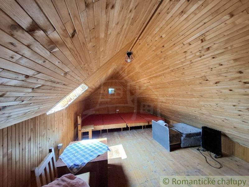 An attic with wooden walls and simple furniture in a cottage.