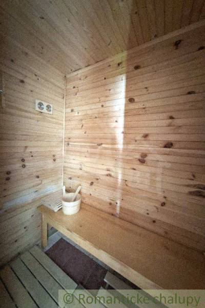Sauna in a wooden interior of a cabin with a ladle and bucket on the bench.