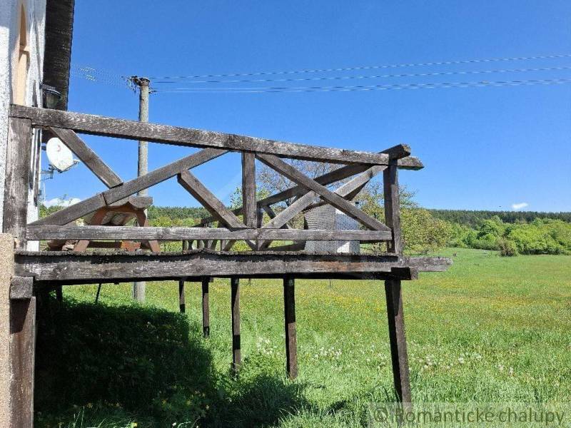 A wooden terrace at the cottage in Podkriváň with a view of the green meadow.