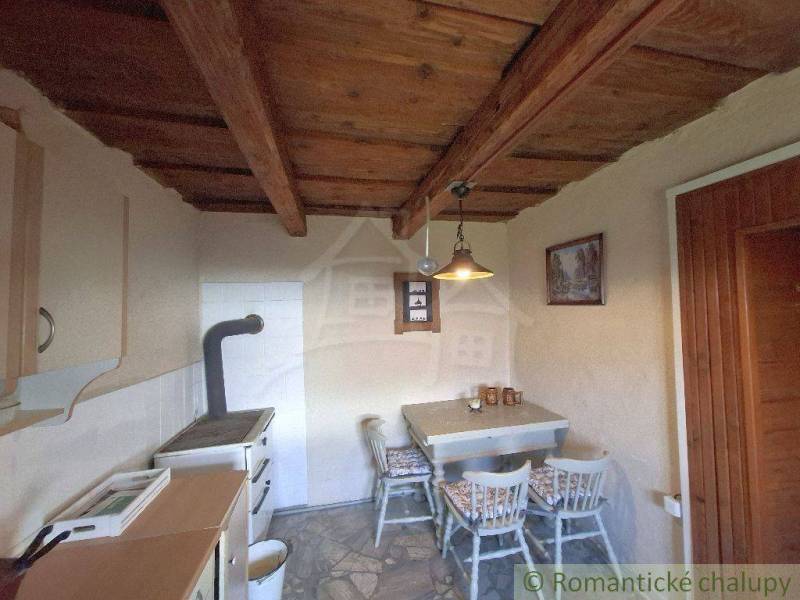 Interior of the Cottage: wooden ceiling, table with chairs, stove. Rustic atmosphere.