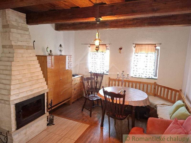 Wooden beams in the cabin with a fireplace and dining table create a cozy atmosphere.