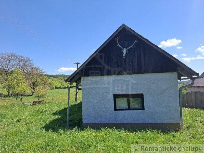 A cottage in Podkriváni with a simple facade in a natural setting under a blue sky.