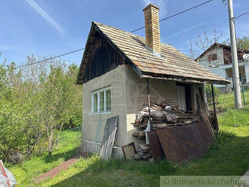 A family house in Kokava nad Rimavicou with a wooden roof and a pile of wood by the gate.