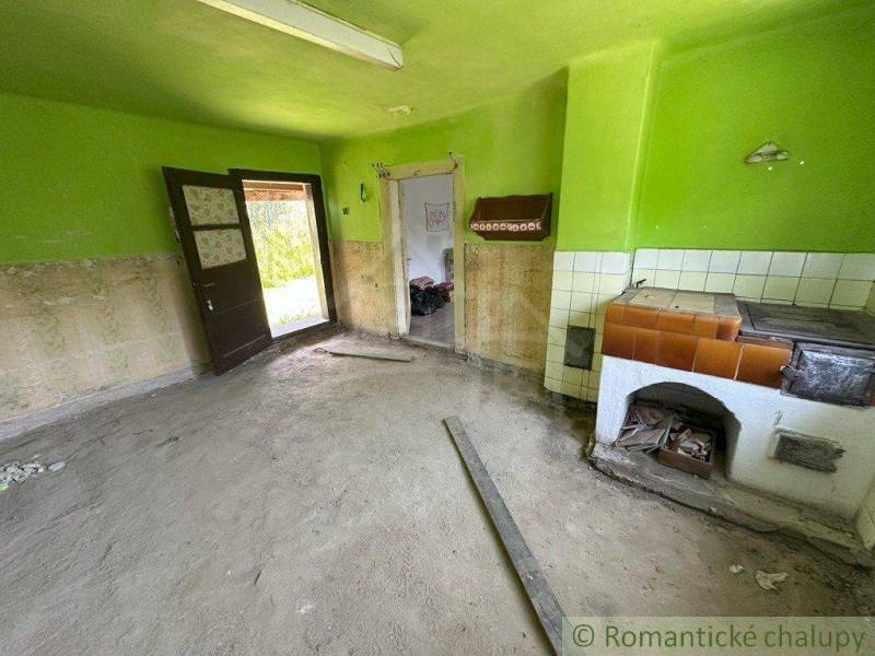 A dusty room in a family house with an old stove and green walls.